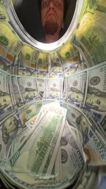 Dikey video. Cam Kavanozun İçinde Yakından Bakış Bir El Yığından 100 Dolarlık banknotları Çekerken Sayım Nakitinin Hareketini Çekerken. Mali Geri çekilme Yasası