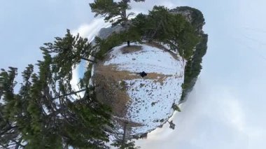 Küçük gezegen etkisi, yoğun çam ağaçları ve bulutlu bir gökyüzünün altındaki uzak tepelerle çevrili karla kaplı bir dağ yolunda yürüyen bir adamı gösteriyor. Gerçeküstü Kış Yolculuğu