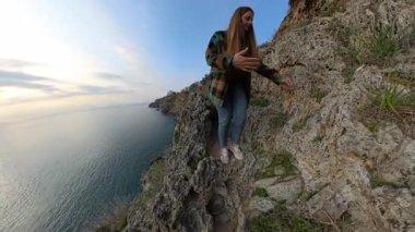 Dik Kayalık Kayalık Kayalıklardan Dikkatlice İnen Bir Dişi Gezgin, Çevresi Bitki örtüsü ve Okyanusa Bakış Alıyor. Solo Sahil Macerası