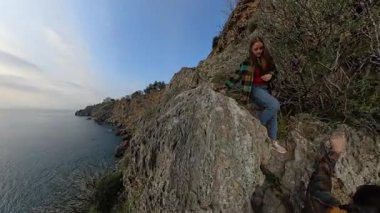 Bir Erkek Gezgin Bir Kadın Gezgine Yardım Ediyor Bir Kayalık Yoldan Aşağı Tırmanırken, Sebze ve Sarkık Kayalarla çevrelenmiş. Destekleyici Kıyı İnişi