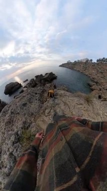 Dikey video. Okyanus kıyısındaki Jagged Kayalıklarda Yürüyen Bir Adam, İlk Kişi Bakış Açısı 'ndan Yakalandı ve Omuzlarına Taktı. Zorlu Sahil Macerası