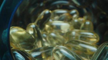 Bulanık Arkaplanlı Açık Mavi Lid 'den dökülen Altın Şeffaf Balık Yağı Kapsülleri, Macro Dolly