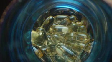 Görünümü Parlak Işık, Makro Perspektif ile aydınlatılmış Jelatin Balık Yağı Kapsülleriyle dolu Mavi Şeffaf Kavanoza Kapat