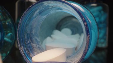 Arka planda Mavi Ek Şişeli Açık Mavi Lid Tutma Beyaz Tabletleri, Macro Işıklandırma Geliştirme Detayları Dolly kaydırma, kapatın.