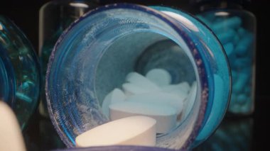 Parmakçılar, arka planda takviye şişeleri ve kapsülleri olan Mavi Lid 'den beyaz bir tablet seçiyor, Dolly slider, kapat..