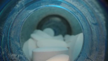Beyaz Oval Tabletlerle Dolu Mavi Ek Şişenin İçinde Yakından Görüntü, Yumuşak Parlak Dolly sürgüsüsüsüsüsüsüsüyle aydınlatılmış, yakın çekim.