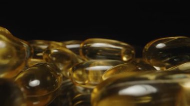 Altın Şeffaf Omega 3 Kapsüllerinin Dolly Kaydırıcısı Pürüzsüz Dokularını Vurguluyor ve Karanlık Arkaplan Besleyici Yansımalarına Yansıtıyor