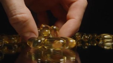 Pürüzsüz Doku ve Parlak Görünüm Sağlıklı Yaşam 'ı gösteren Yansıtıcı bir yüzeyden Altın Şeffaf Kapsül Seçen Parmaklar