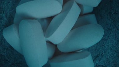 Mavi Kavanozun İçinde Beyaz Oval Tabletlerin Kapanışı. Kamera yukarı doğru hareket ediyor. Pürüzsüz dokularını ve günlük besinlerini yakalıyor.