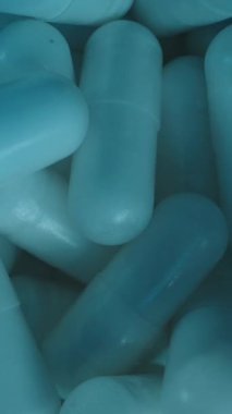 Dikey video. Beyaz Kapsülleri Mavi Kavanozun İçinde Kapat Kamera Yukarı Kayarken Işıltılı Yüzeylerini ve Dağıtım Sağlığını ve Sağlık Bakımını Vurguluyor