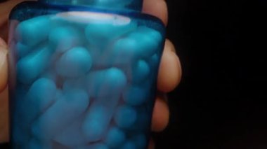 Beyaz Kapsüller Mavi Şişe 'den bir ele akıyor Pürüzsüz yüzeyi ve Parlak Sağlık ve Sağlık Bakımını Gösteriyorlar