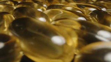 Yansıtıcı Siyah Arkaplan Beslenme Temelinde Vurgulanan Yalnız Kapsüle Giden Altın Omega 3 Kapsülleri Kümesi boyunca Hareket