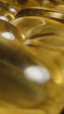 Dikey video. Yansıtıcı Siyah Arkaplan Beslenme Temelinde Vurgulanan Yalnız Kapsüle Giden Altın Omega 3 Kapsülleri Kümesi boyunca Hareket