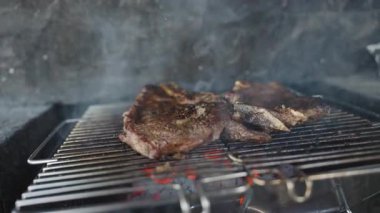 Duman ve Alevlerle çevrili Yavaş Çekimde Biftek Pişirme Kömür Kömürleri Kömürleşmiş Dokuları ve Cızırdayan Açık Hava Barbeküsü