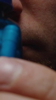 Dikey video. Mavi Kapsül Şişesi Tutan Bir Adamın Yakın Çekimi Canlı Renklerini ve Parlak Doku Sağlığını ve Sağlık Bakımını Vurguluyor