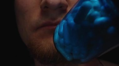 Kapsüllerle dolu Mavi Şişeyi İncelemekte olan Bir Adam Yumuşak Doku ve Hapların Derin Renklerini Göstermektedir Beslenme Farkındalığı