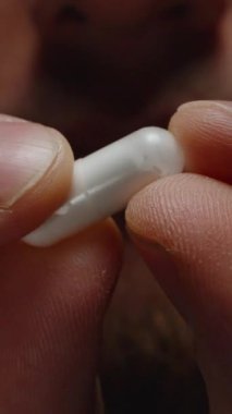 Dikey video. Parmaklar Arasında Beyaz Kapsülü Tutan Eller Yumuşak Dokusunu ve Özgeçmişine Karşı Detaylarını Vurguluyor
