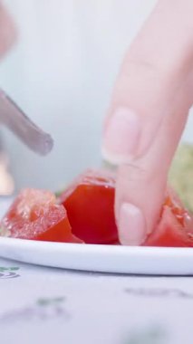 Dikey video. Bıçakla Bir Tabakta Taze Domatesleri Dilimleyen Bir Kişi, Elleri Tutma ve Kılavuz, Canlı Kırmızı Renge Odaklan