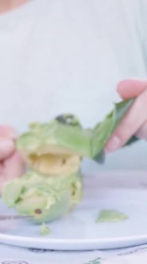 Dikey video. Avokado Derisini Bıçakla Soyup Beyaz Tabakta Yarısı Avokado Hazırlayan Bir Kişi
