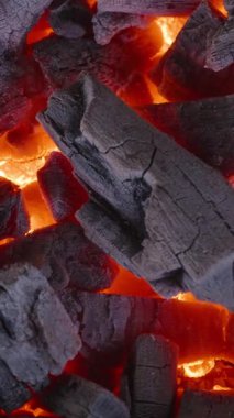 Dikey video. Şiddetli Isı ve Kırmızı Turuncu Renkler saçan Parlayan Kömür Parçalarının Aşırı Yakın Çekimi, Çerçeveyi Doldurma