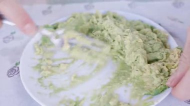 Çatalla bir tabakta insan ezme Avokadosu, Pürüzsüz Yayılabilir bir doku, Yakın planda Eller Görünür