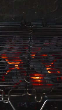 Dikey video. Metal Izgara Parlayan Kömürün Üzerinde Turuncu Alevler, Kararmış Barbekü Çukuru 'nun İçinde Konumlandırılmış