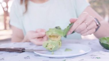 Avokado Derisini Bıçakla Soyup Beyaz Tabakta Yarısı Avokado Hazırlayan Bir Kişi