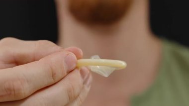 Latex Dokusuna Odaklı Bir Kondom Yakın Çekim, Arka planda Bir Erkek figürü, Bulanık, İyi-Aydınlatma Ortamı