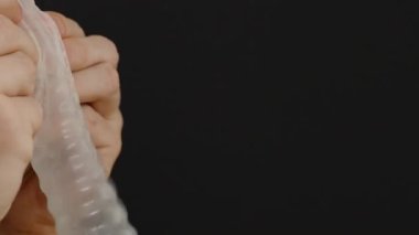 Siyah Arkaplan Karşısında Balon Gibi Kondom Şişirerek Oynayan Bir Adam Neşeli ve Alışılmadık Kullanım Gösteriyor