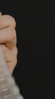 Dikey video. Siyah Arkaplan Karşısında Balon Gibi Kondom Şişirerek Oynayan Bir Adam Neşeli ve Alışılmadık Kullanım Gösteriyor