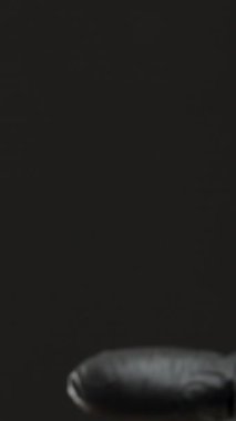 Dikey video. Siyah Eldiven Giyen El Avuç İçindeki Kondomu Tutuyor, Güvenli Tutma ve Temizlik Uygulamalarını Gösteriyor