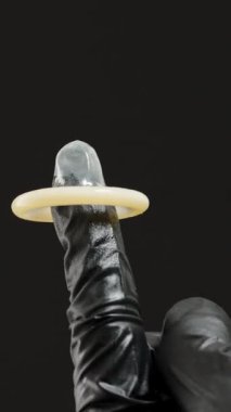 Dikey video. Siyah Eldivenli Bir El Kullanılmış Kondomu Çimdikliyor ve Denetiyor, Uygun Tutma ve Güvenliği Gösteriyor