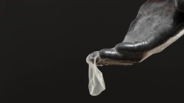 Siyah Eldivenli Bir El, Parmaklarına Uzanmışken Bir Prezervatifi Şişiriyor, Esnekliği ve Yaratıcılığı Gösteriyor