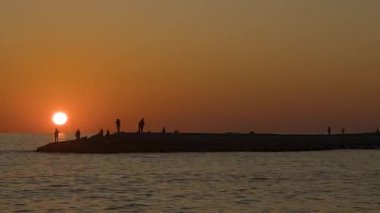 Balıkçıların Zaman Hızı Balık Çubuklarını Deniz Üzerindeki Rocky Rıhtımında Silüet 'te Turuncu Gökyüzü' ne Atar