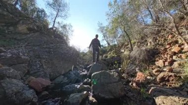 Dağlık bir ormanda, Kayalıklarda Yürüyen Bir Adam Güneş Işığıyla Sahneyi Işıklandırıyor