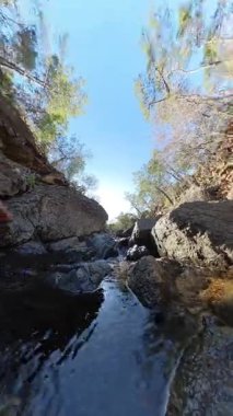 Dikey video. Berrak Gökyüzü ve Gün Işığıyla Rocky Dağlık Alanında Küçük Şelale