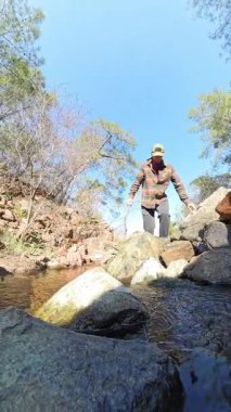 Dikey video. Düşük Açı Perspektif ve Güneş Işığıyla Küçük Kayalık Bir Ormanda Yürüyen Adam