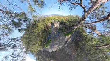 Sırt çantalı bir adam Forested Hills 'in Manzarası' nı, bir sahil kasabasını ve bir uçurumdan uzak dağları hayranlıkla seyrediyor.