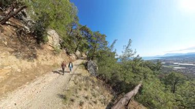 Kayalık Dağ Yolu 'nda tepeye tırmanan erkek ve kadın, Arkaplan Sahili Manzaralı Uçurumun Kıyısında Düşen Ağaca Yaklaşıyor.