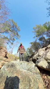 Dikey video. Dinamik Perspektif Vurgulama Hareketi ve Macerası ile Küçük Akıntıya Atlayan Bir Yürüyüşçünün Düşük Açı Çekimi