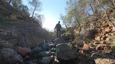 Dağlık bir ormanda, Kayalıklarda Yürüyen Bir Adam Güneş Işığıyla Sahneyi Işıklandırıyor