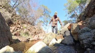 Düşük Açı Perspektif ve Güneş Işığıyla Küçük Kayalık Bir Ormanda Yürüyen Adam