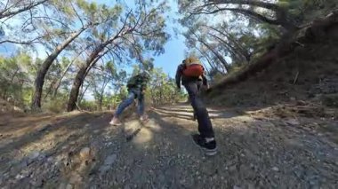 Uzun Ağaçlarla çevrili dik bir ormana tırmanan iki gezgin, Küçük Gezegen Efekti ile yakalanarak Küresel bir Perspektif Oluşturuyor