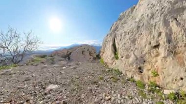 Kamera İki Büyük Kayalık Arasında Dar Bir Boşluktan Geçerek Açık Mavi Gök Altında Dağın Altındaki Deniz, Şehir ve Vadi 'nin Çarpıcı Manzarasını Gösteriyor.