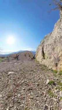 Dikey video. Kamera İki Büyük Kayalık Arasında Dar Bir Boşluktan Geçerek Açık Mavi Gök Altında Dağın Altındaki Deniz, Şehir ve Vadi 'nin Çarpıcı Manzarasını Gösteriyor.