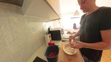 Siyah Tişörtlü Kadın Modern Kitchen 'da Tabak Üstünde Kaynamış Yumurta Kabuğu Kabukluyor Yanında Doğranmış Sebzeler, Geniş Açı Görünüm