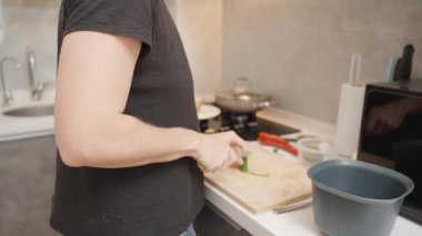Modern Kitchen 'da Ahşap Kesme Kurulunda Odun ve Malzemeleri Yakınındaki Yan Görüş' te Siyah Tişört Kesen Kadın Taze Salatalık