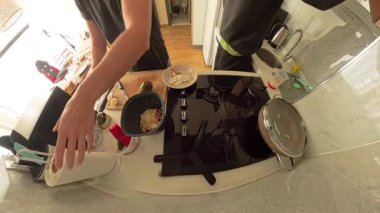 Modern Kitchen 'da Siyah Tişörtlü Kadın Ahşap Kesme Avokadosu' nu ikiye bölerken Diğer Bir Kişi Bulaşıkları Yıkarken, Geniş Açı Görüş