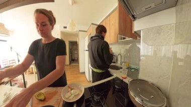 Siyah Tişörtlü Kadın Ahşap Kesme Avokadosu Kapüşonlu Adam Modern Mutfakta Bulaşıkları Yıkarken, Geniş Açı Görünüm