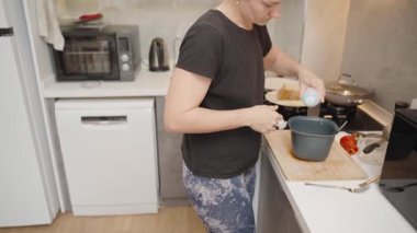 Modern Kitchen 'daki Siyah Tişörtlü Kadın Tahta Kesme Kuruluna Tuz Ekliyor